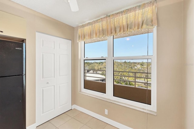 interior space with a ceiling fan, baseboards, and light tile patterned floors