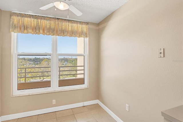 spare room featuring a ceiling fan, a textured ceiling, baseboards, and light tile patterned floors