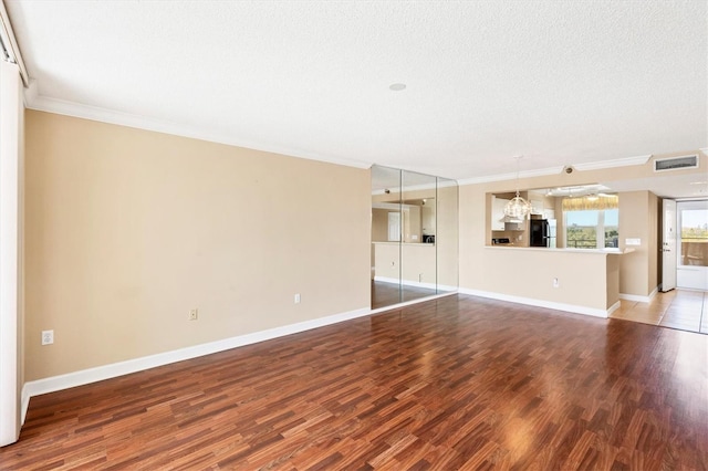 unfurnished living room with visible vents, ornamental molding, a textured ceiling, wood finished floors, and baseboards