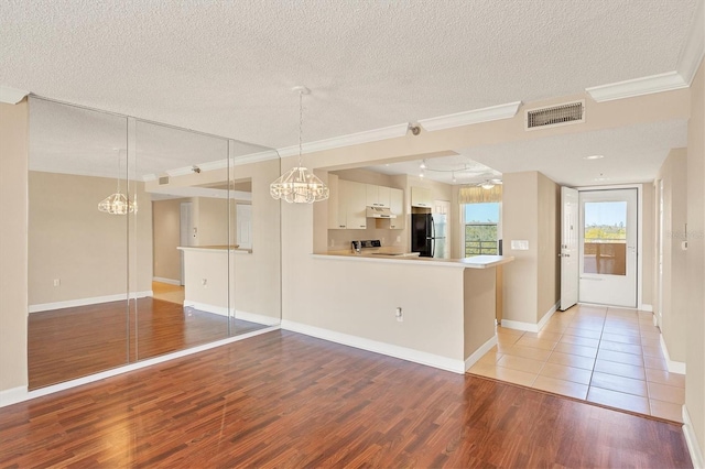 unfurnished room with crown molding, visible vents, a textured ceiling, light wood-type flooring, and baseboards