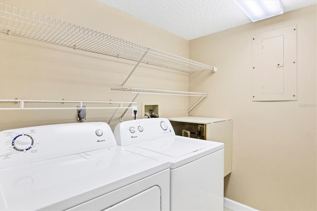 laundry area with a textured ceiling, laundry area, baseboards, electric panel, and washer and clothes dryer