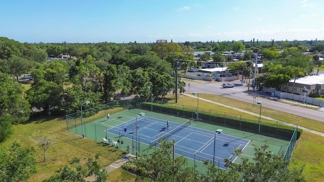 view of tennis court with fence and a yard