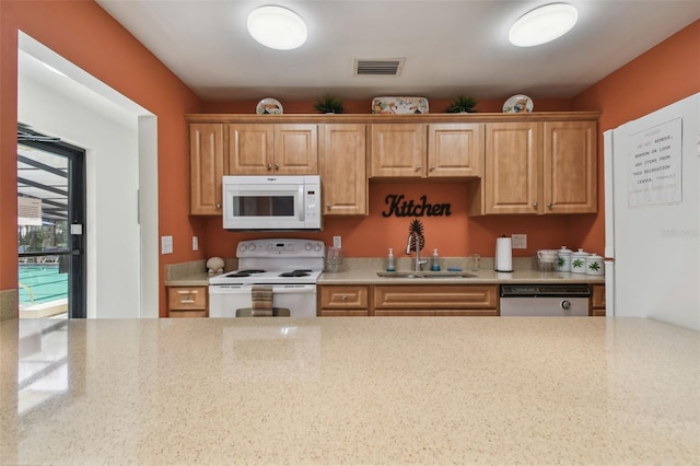 kitchen with white appliances, a sink, visible vents, and light stone countertops