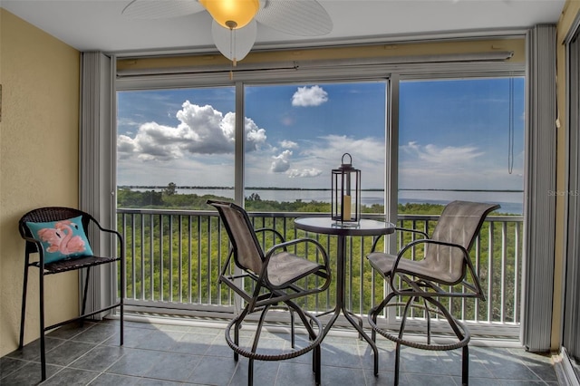 sunroom featuring a water view and ceiling fan