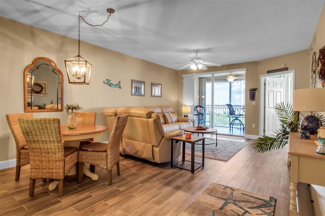 dining room with wood tiled floor, baseboards, and ceiling fan with notable chandelier