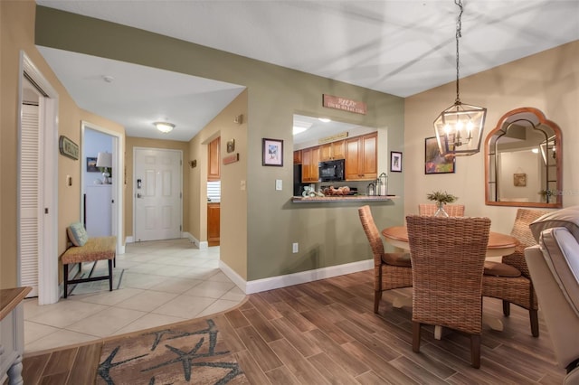 dining space featuring light wood-type flooring, baseboards, and a chandelier