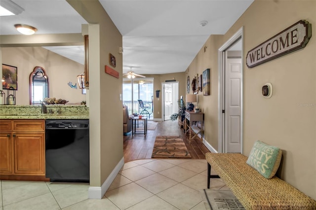 kitchen with ceiling fan, light stone counters, light tile patterned flooring, brown cabinets, and dishwasher