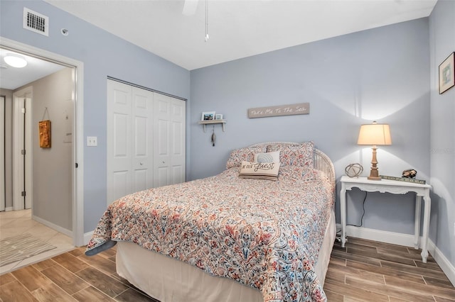 bedroom with baseboards, visible vents, a ceiling fan, wood finish floors, and a closet