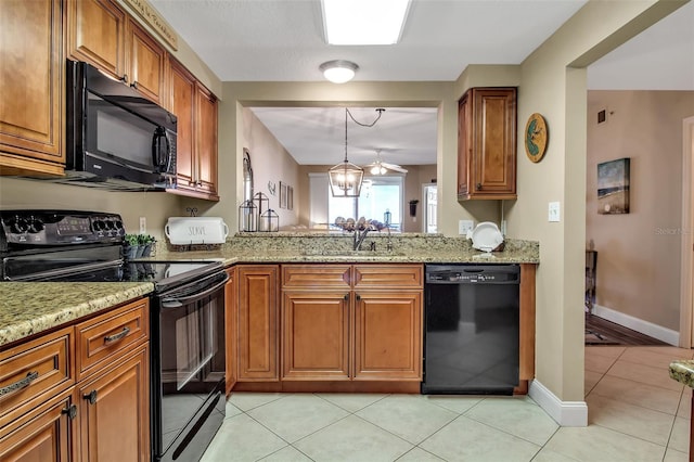 kitchen featuring black appliances, brown cabinetry, a sink, and light stone countertops