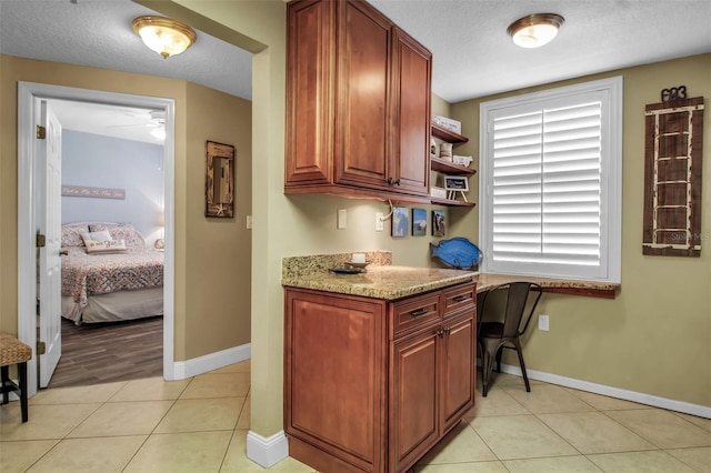 kitchen featuring light tile patterned floors, a textured ceiling, open shelves, and built in desk