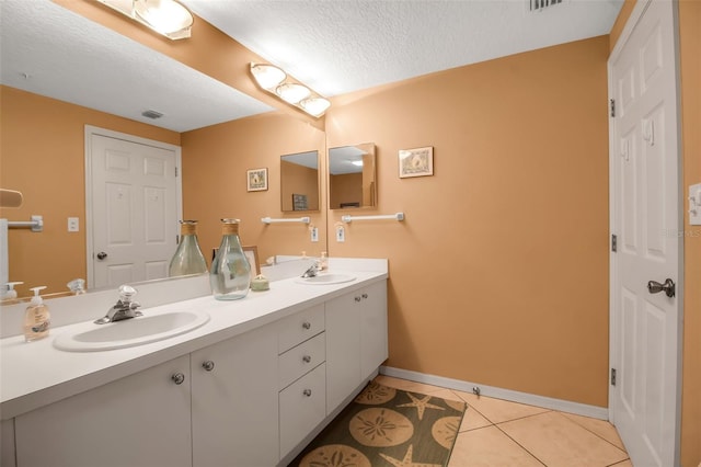 full bathroom with double vanity, a textured ceiling, a sink, and tile patterned floors