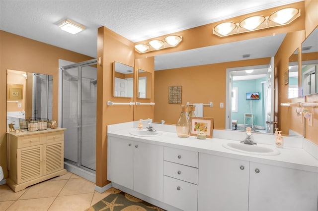 full bathroom with tile patterned flooring, a sink, a shower stall, and double vanity