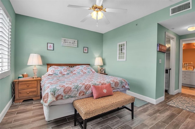 bedroom with baseboards, visible vents, and wood finish floors