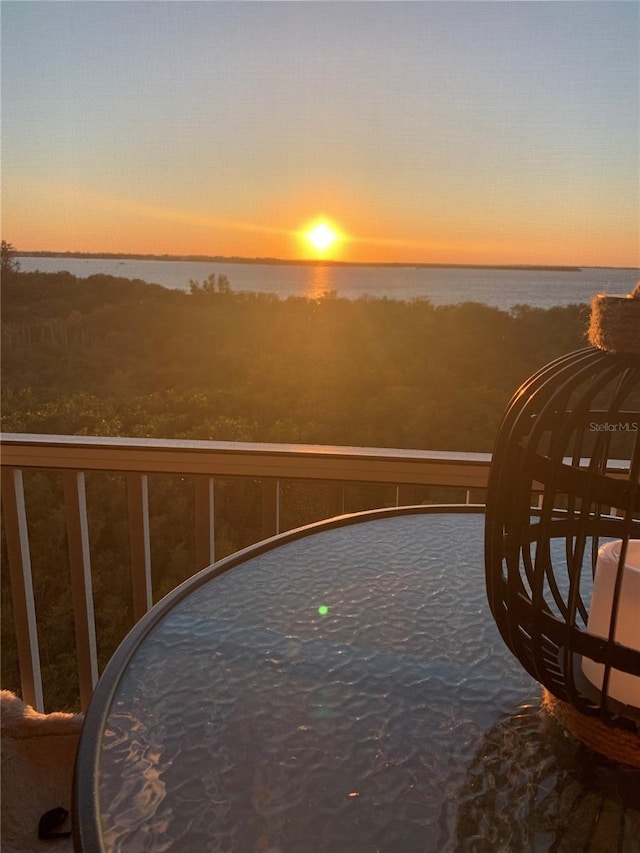 balcony at dusk featuring a water view