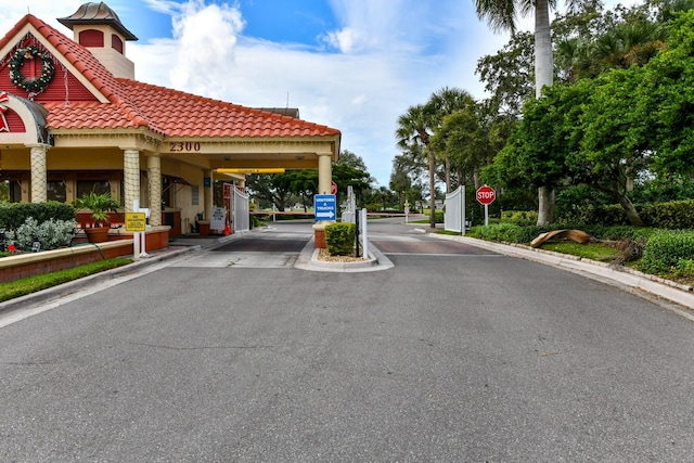 view of road with traffic signs, curbs, and a gated entry