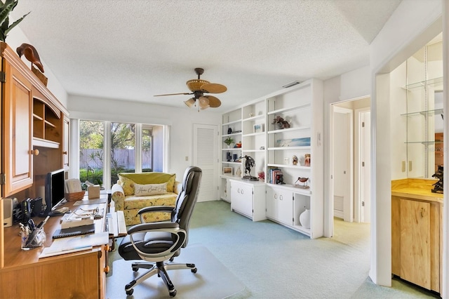 office with a ceiling fan, light carpet, visible vents, and a textured ceiling