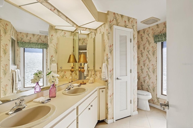 full bath featuring toilet, wallpapered walls, and a sink