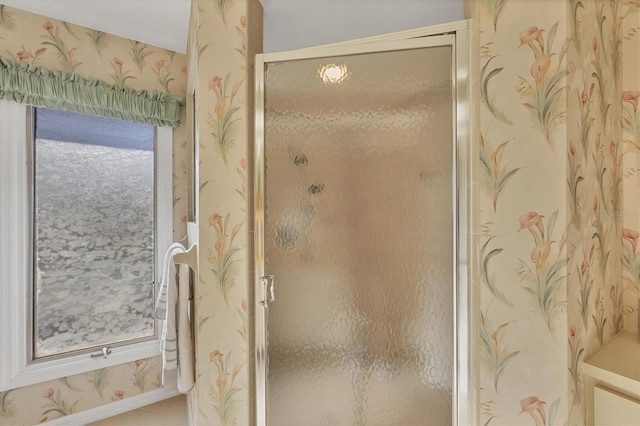 full bathroom featuring a shower stall, baseboards, and wallpapered walls