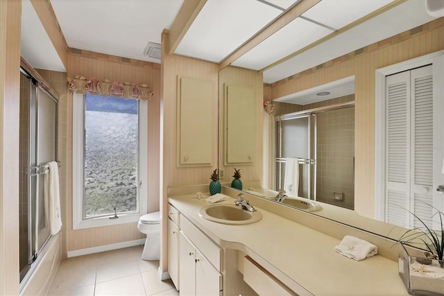 bathroom featuring a closet, toilet, enclosed tub / shower combo, vanity, and tile patterned floors