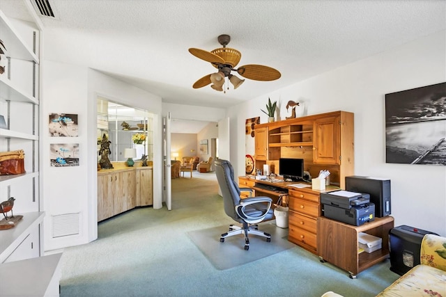 home office with light carpet, ceiling fan, visible vents, and a textured ceiling