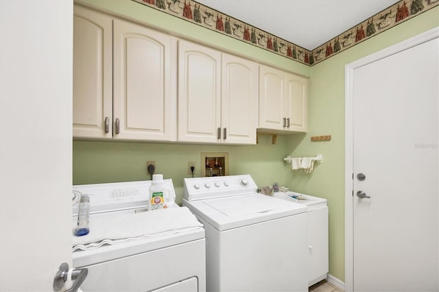 washroom with cabinet space, washing machine and dryer, and baseboards