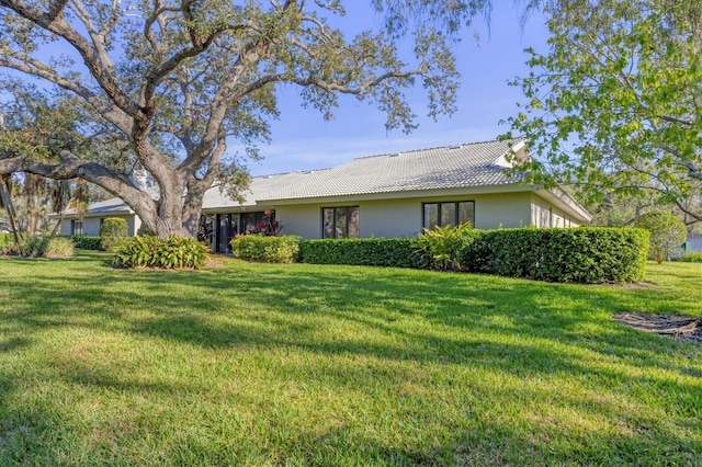 exterior space featuring a tiled roof, a front yard, and stucco siding