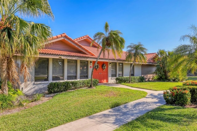 view of front of home with a tiled roof, a front yard, and stucco siding