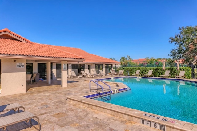 community pool with a patio area and fence