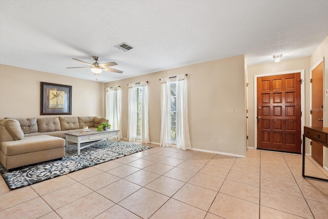 living area featuring baseboards, visible vents, a textured ceiling, and light tile patterned flooring