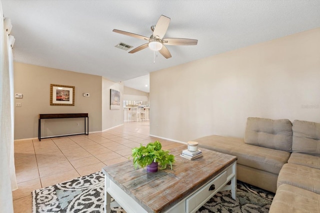 living room featuring baseboards, visible vents, a ceiling fan, a textured ceiling, and light tile patterned flooring