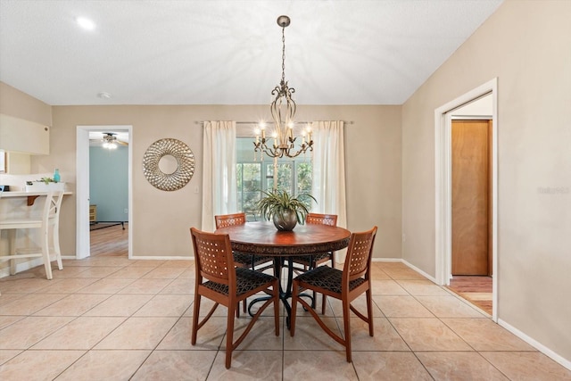 dining area with ceiling fan with notable chandelier, light tile patterned flooring, and baseboards