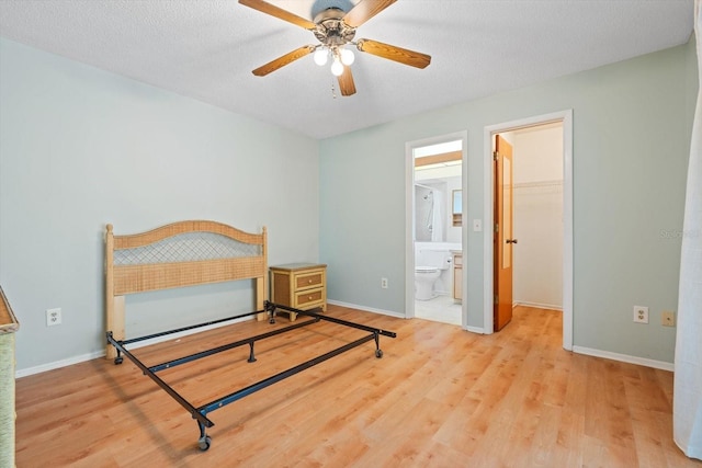 bedroom featuring a textured ceiling, a spacious closet, and light wood finished floors