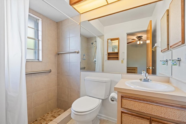 bathroom with toilet, a tile shower, and vanity