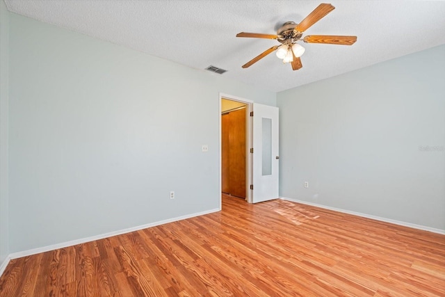 unfurnished room featuring visible vents, light wood-style flooring, a ceiling fan, a textured ceiling, and baseboards