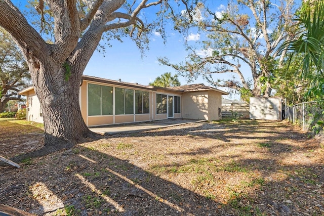 back of house featuring a storage shed, fence, an outdoor structure, and stucco siding