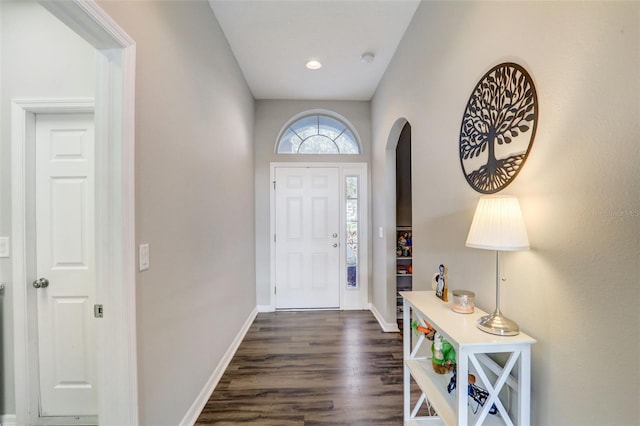 entrance foyer with baseboards, arched walkways, and dark wood-type flooring