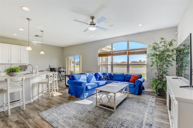 living room featuring ceiling fan, light wood-type flooring, visible vents, and recessed lighting