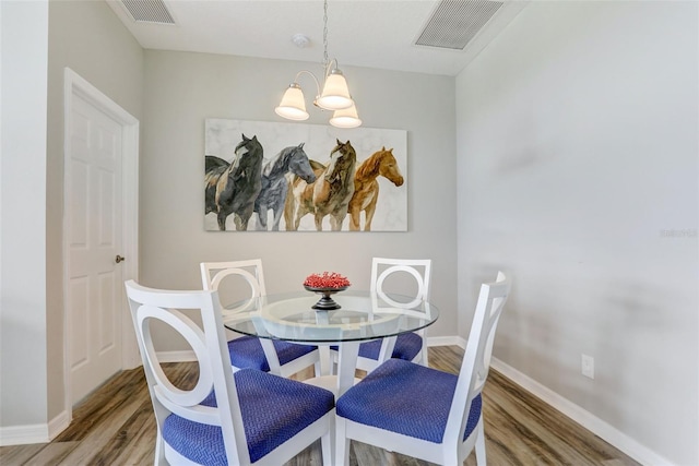 dining room with baseboards, visible vents, a chandelier, and wood finished floors