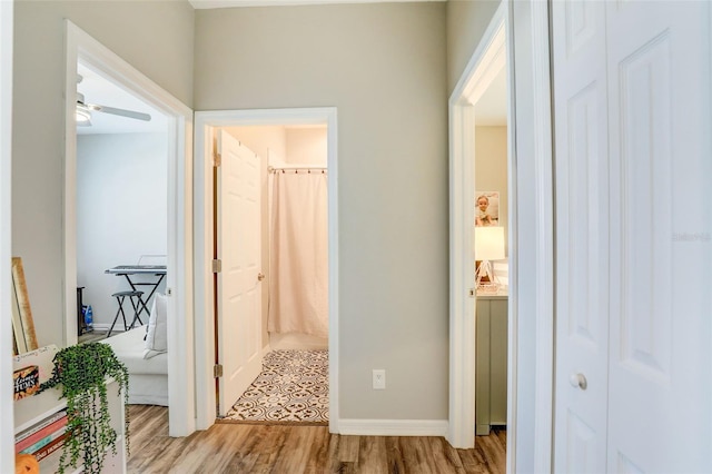 corridor featuring light wood-style floors and baseboards