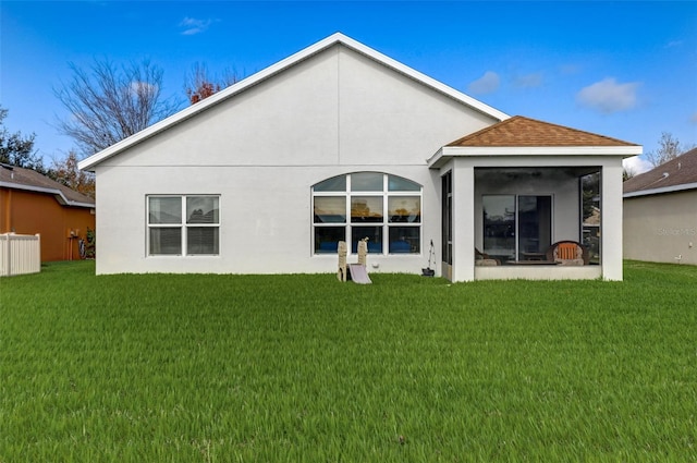 rear view of house featuring stucco siding, roof with shingles, and a yard