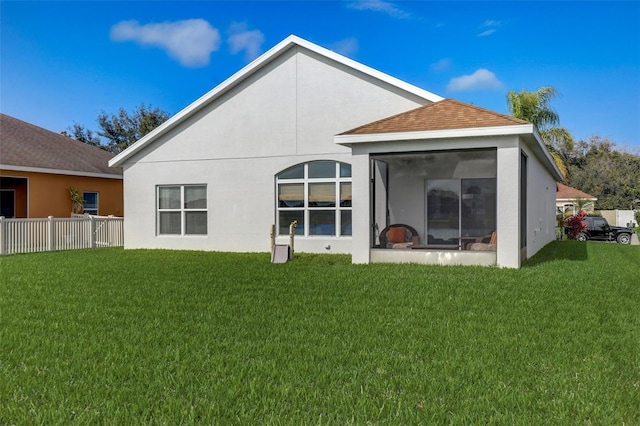 rear view of house featuring a shingled roof, fence, a sunroom, a yard, and stucco siding