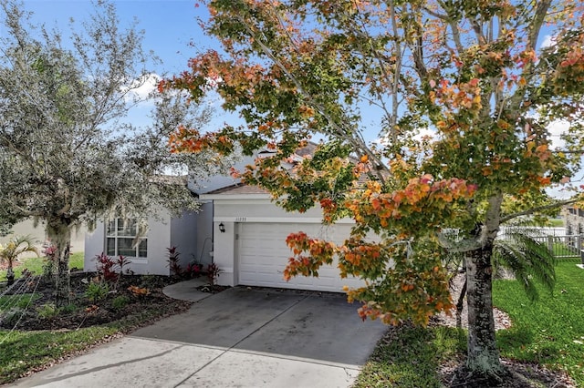 view of front facade with driveway, fence, an attached garage, and stucco siding