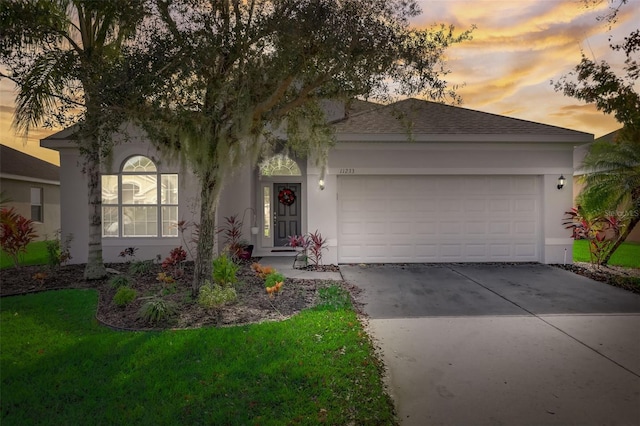 ranch-style house featuring a garage, concrete driveway, a shingled roof, and stucco siding