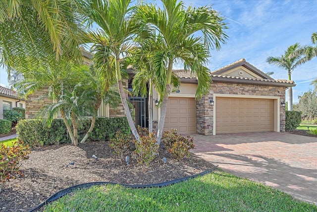 view of front of home with decorative driveway, stucco siding, a garage, stone siding, and a tiled roof