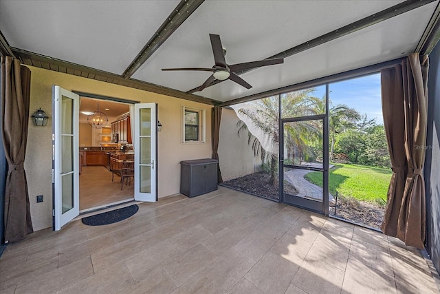 unfurnished sunroom with ceiling fan with notable chandelier