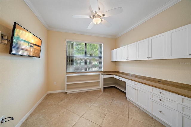 unfurnished office featuring light tile patterned floors, baseboards, a ceiling fan, built in study area, and crown molding