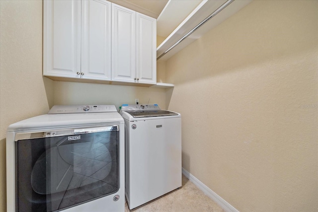 washroom with separate washer and dryer, cabinet space, and baseboards