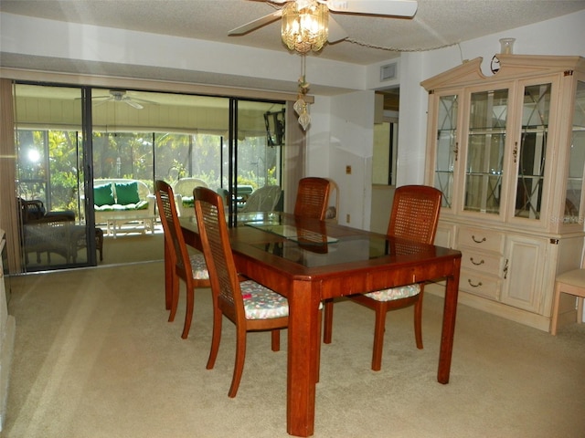 carpeted dining room featuring a ceiling fan, a sunroom, visible vents, and a textured ceiling