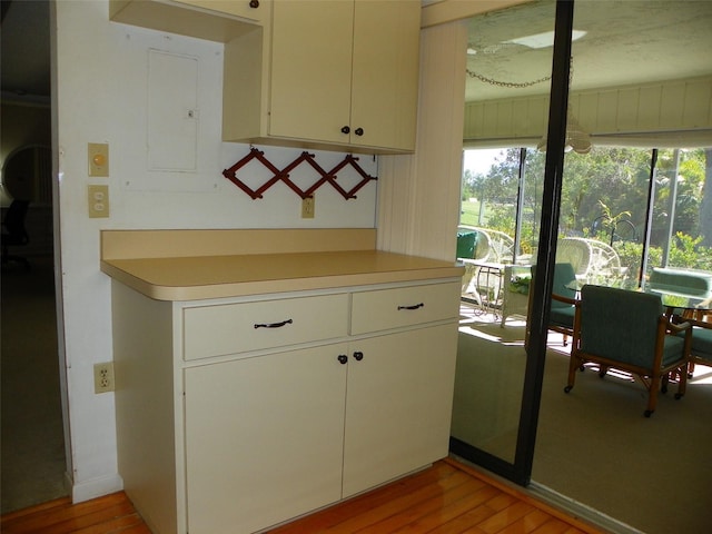 kitchen with white cabinets, light wood finished floors, electric panel, and light countertops