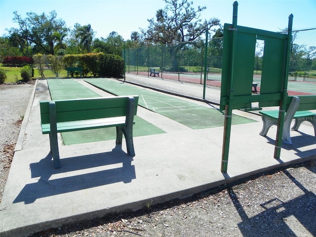 surrounding community featuring a tennis court, fence, and shuffleboard